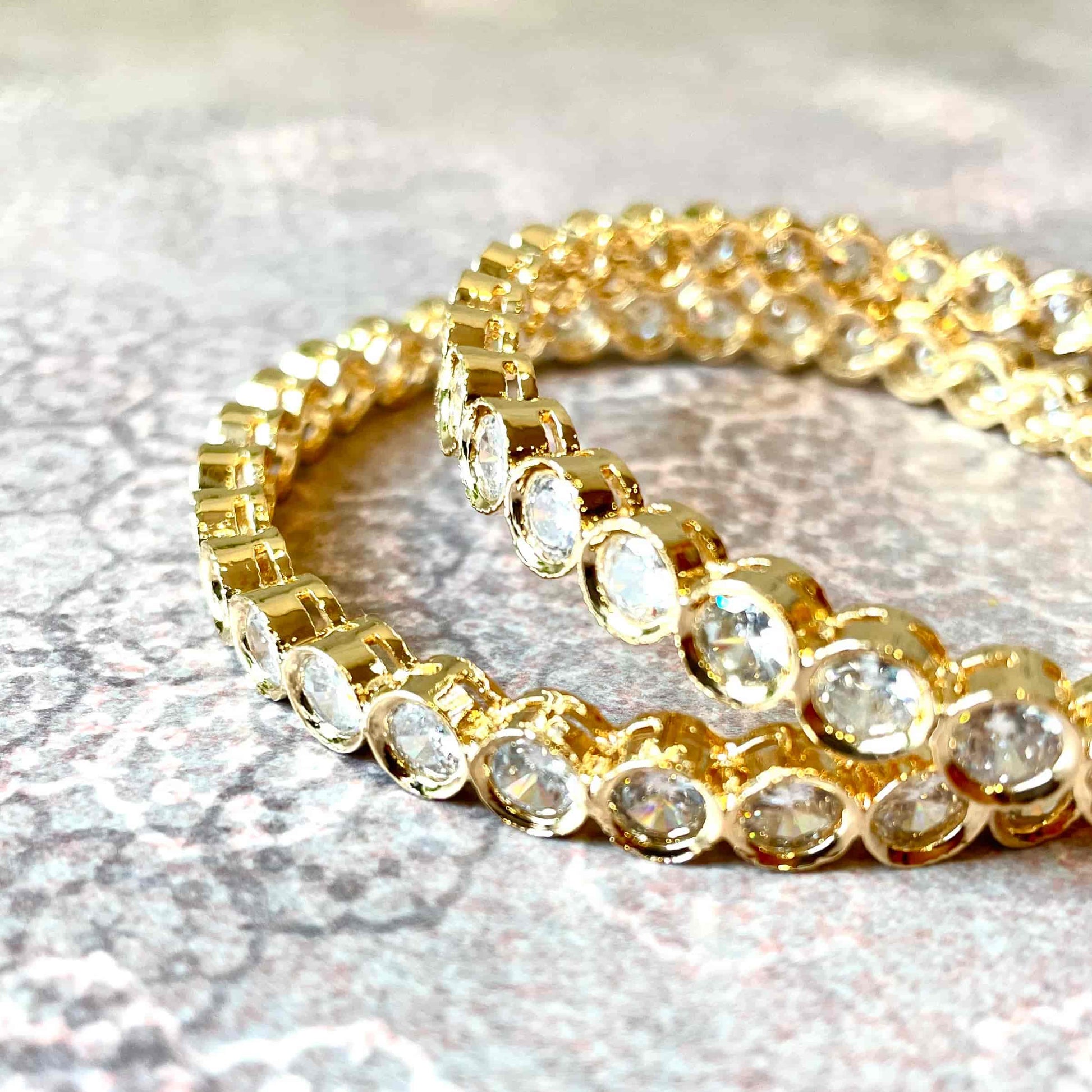 Gold and clear beaded bracelets/bangles on a textured surface