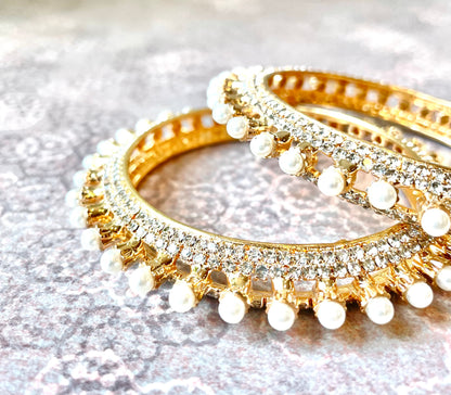 Gold bangles with pearl and crystal embellishments on a light background